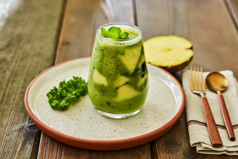 Copo alto com smoothie verde e folhas de hortelã